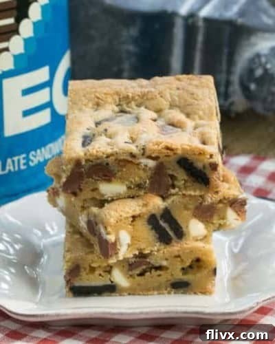 A hand holding a perfectly sliced Oreo Chocolate Chip Bar, ready to be enjoyed, with more bars visible in the background.