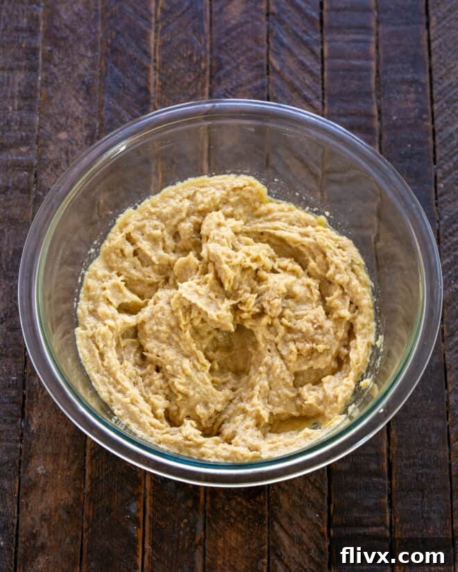 Close-up of butter and sugars being creamed together in a stand mixer, creating a light and fluffy mixture.
