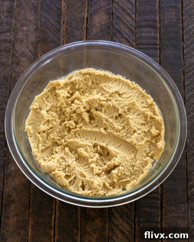 Dry ingredients (flour, baking soda, baking powder, salt) being added to the wet cookie dough mixture.