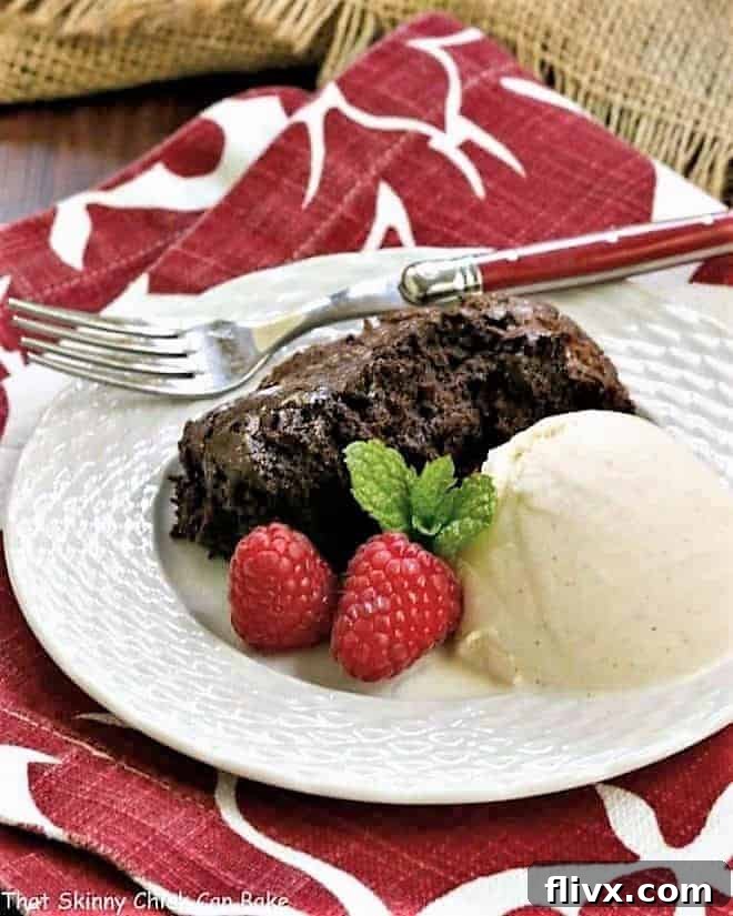 Slow Cooker Brownie Dessert - A delectable chocolate treat made in a slow cooker! A scoop of rich Slow Cooker Brownie Dessert on a white plate, elegantly garnished with a dollop of vanilla ice cream and fresh, vibrant raspberries.