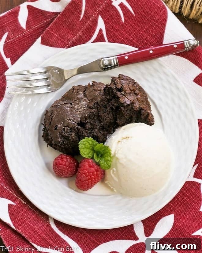 Slow Cooker Brownie Dessert - A delectable chocolate treat made in a slow cooker! Overhead view of a single scoop of Slow Cooker Brownie Dessert on a white plate, accompanied by a sleek red-handled fork, highlighting its rich, fudgy texture.
