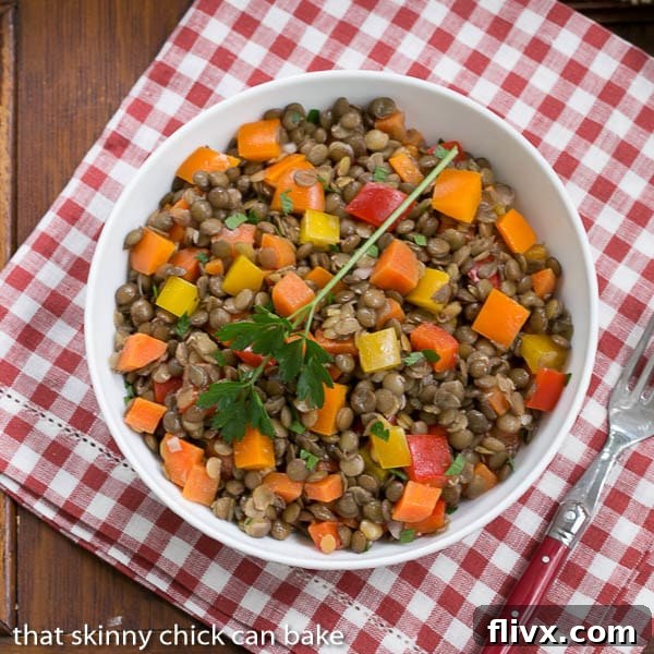 French Lentil Salad elegantly arranged in a white bowl, set against a classic red and white checked napkin, highlighting its rustic charm.