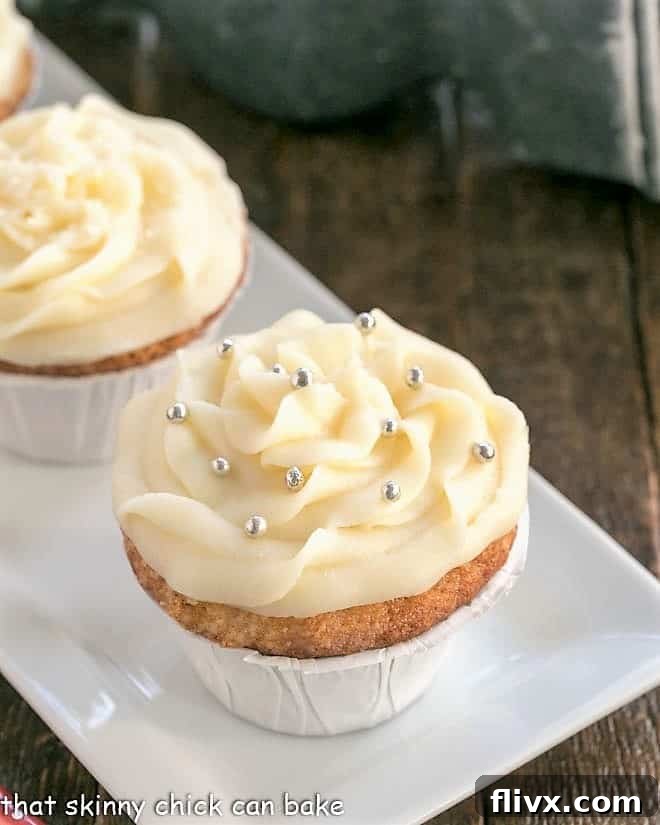 Vanilla cupcakes adorned with generous swirls of cream cheese frosting, elegantly arranged on a pristine white serving tray.