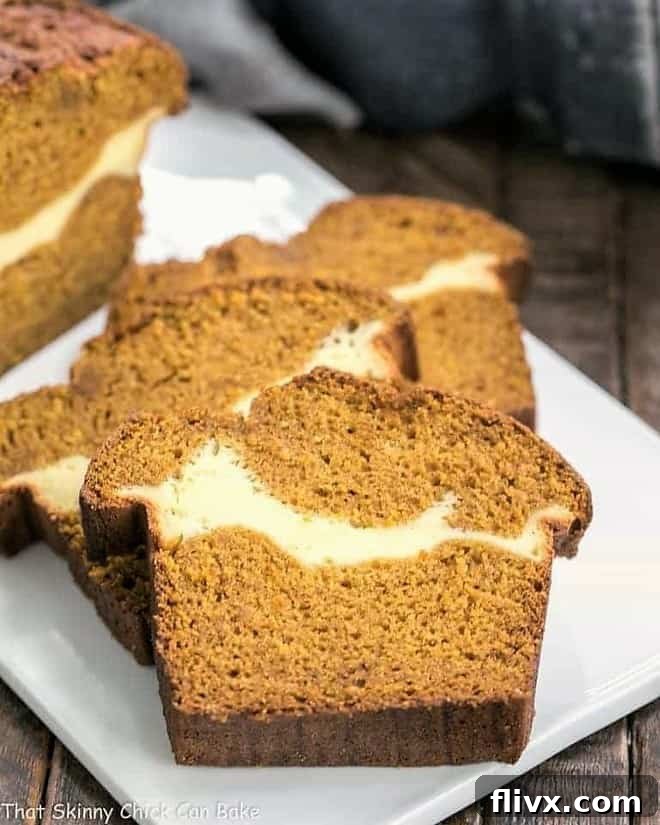 Slices of Cream Cheese Filled Pumpkin Bread neatly arranged on a pristine white platter, showcasing the beautiful swirl of cream cheese filling within the moist pumpkin loaf.