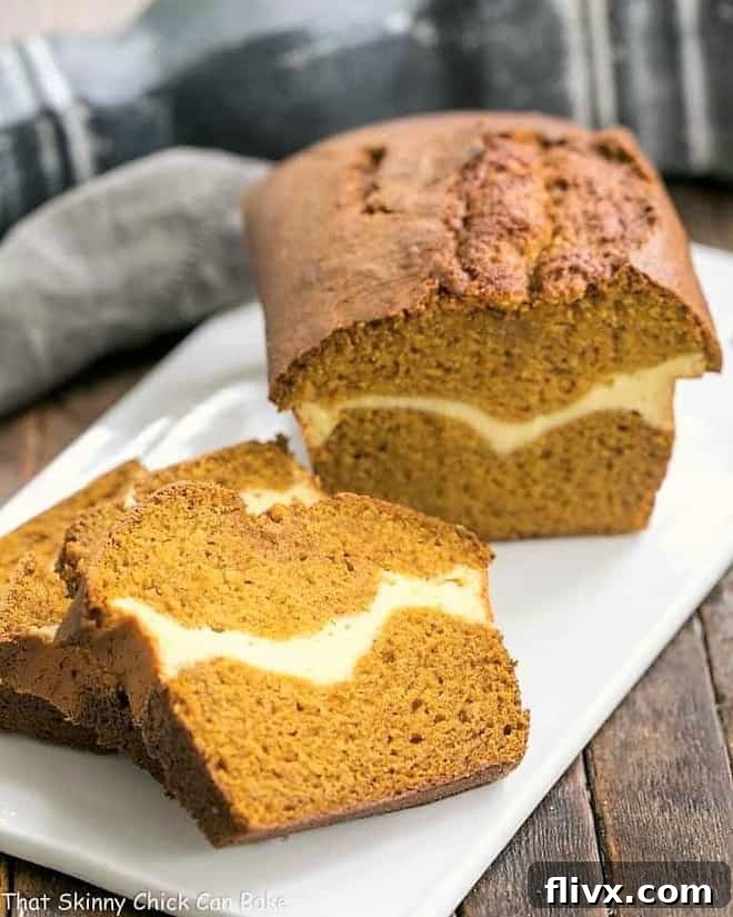 A freshly baked Cream Cheese Filled Pumpkin Bread loaf on a white ceramic cutting board, with several slices already cut and ready to serve.