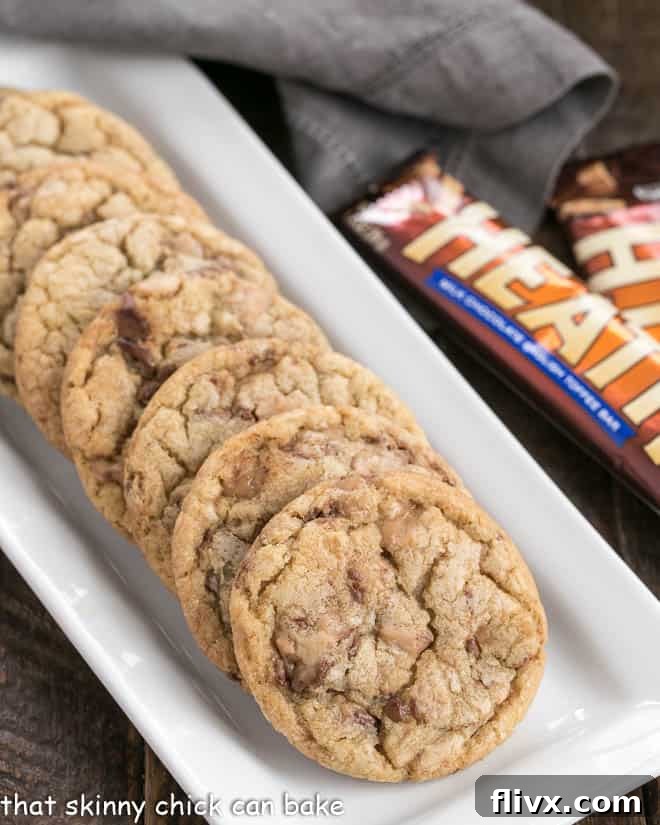 Perfectly baked Brown Butter Toffee Cookies cooling on a white tray, showcasing their golden edges and delicious toffee bits.