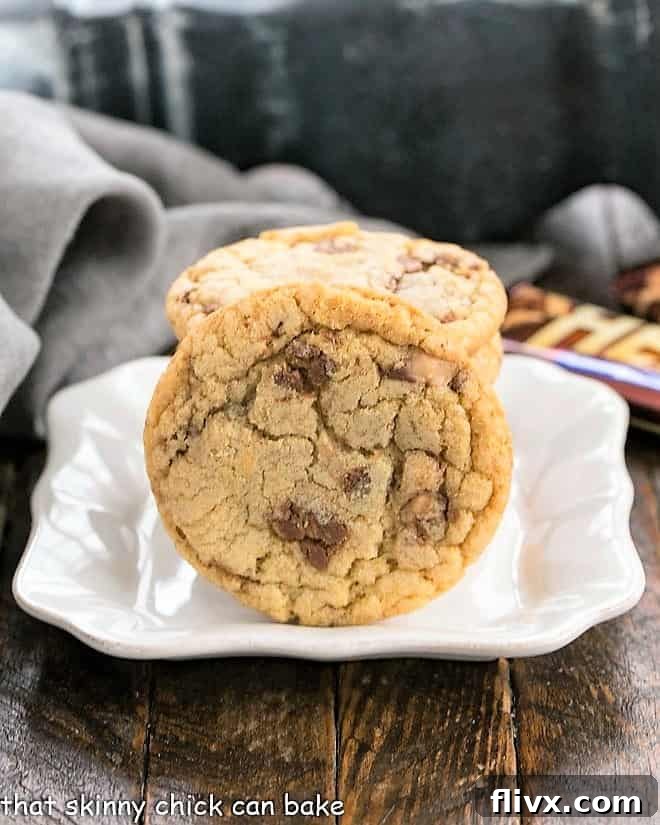 Close-up of a single Brown Butter Toffee Cookie on a small square ceramic plate, highlighting its chewy texture and visible toffee pieces.