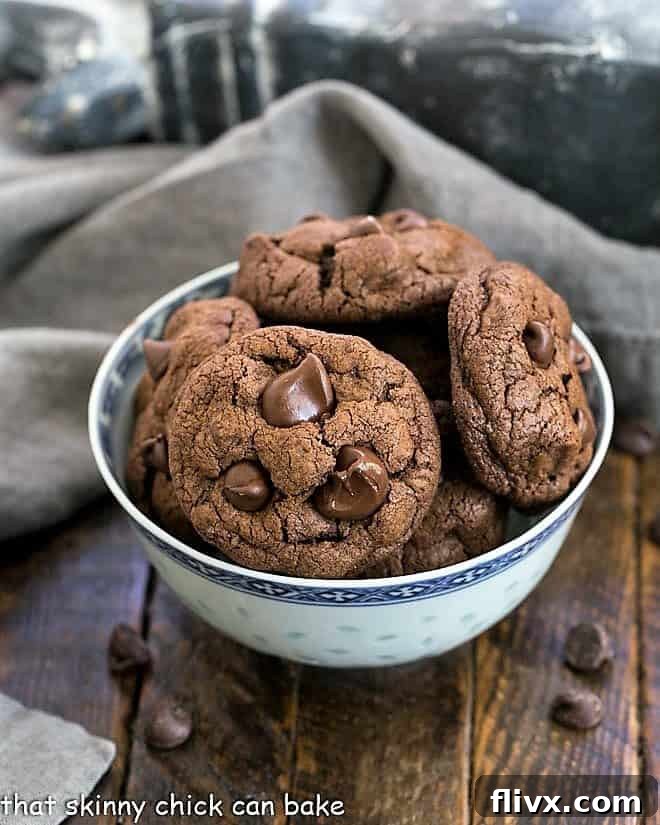 A vibrant, close-up shot of Double Chocolate Chunk Cookies, nestled invitingly in an elegant Asian blue bowl, highlighting their rich texture and generous chocolate pieces.