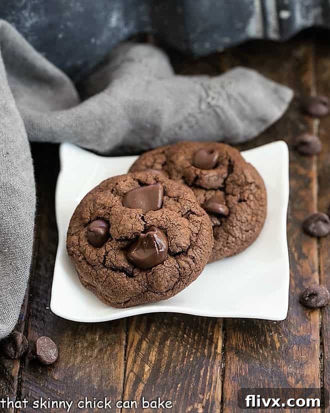 Two exquisite Double Chocolate Chunk Cookies resting on a sleek square white plate, perfectly showcasing their dark, rich color and abundant chocolate chunks, promising a delicious experience.