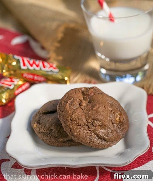 Two Double Chocolate Twix Cookies on a white plate with a refreshing glass of milk, inviting a delicious treat