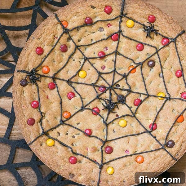 A festive Spiderweb Cookie Cake adorned with colorful M&M's, resting on a spooky felt spiderweb for a perfect Halloween display.