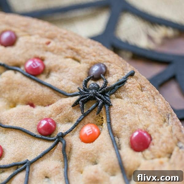 Close-up of a perfectly piped Spiderweb Cookie Cake, featuring a realistic plastic spider for an extra spooky Halloween touch.