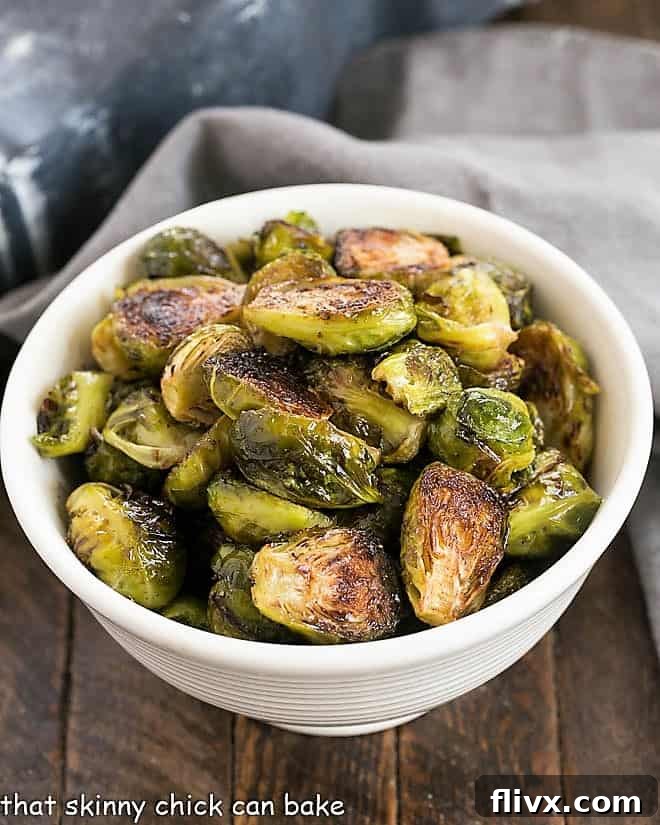 An inviting overhead view of a white serving bowl brimming with perfectly roasted honey balsamic Brussels sprouts, showcasing their beautiful caramelization and glistening glaze.