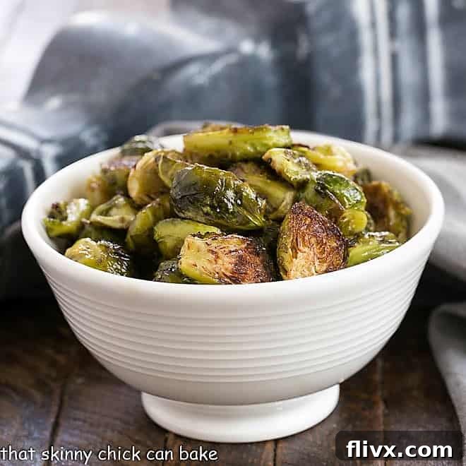 Roasted Brussels sprouts in a white ceramic bowl, garnished with fresh herbs.