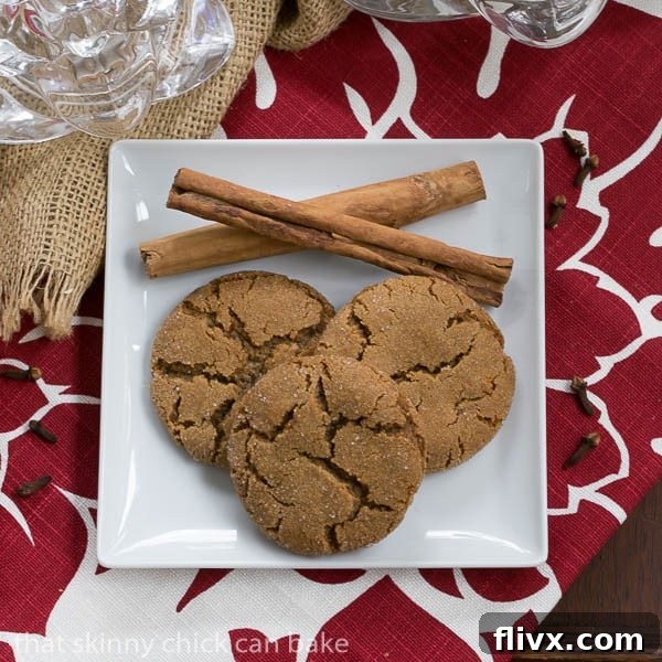 Close-up overhead shot of Triple Ginger Snaps with decorative cinnamon sticks on a white ceramic plate, showcasing their perfect texture and inviting golden-brown hue.