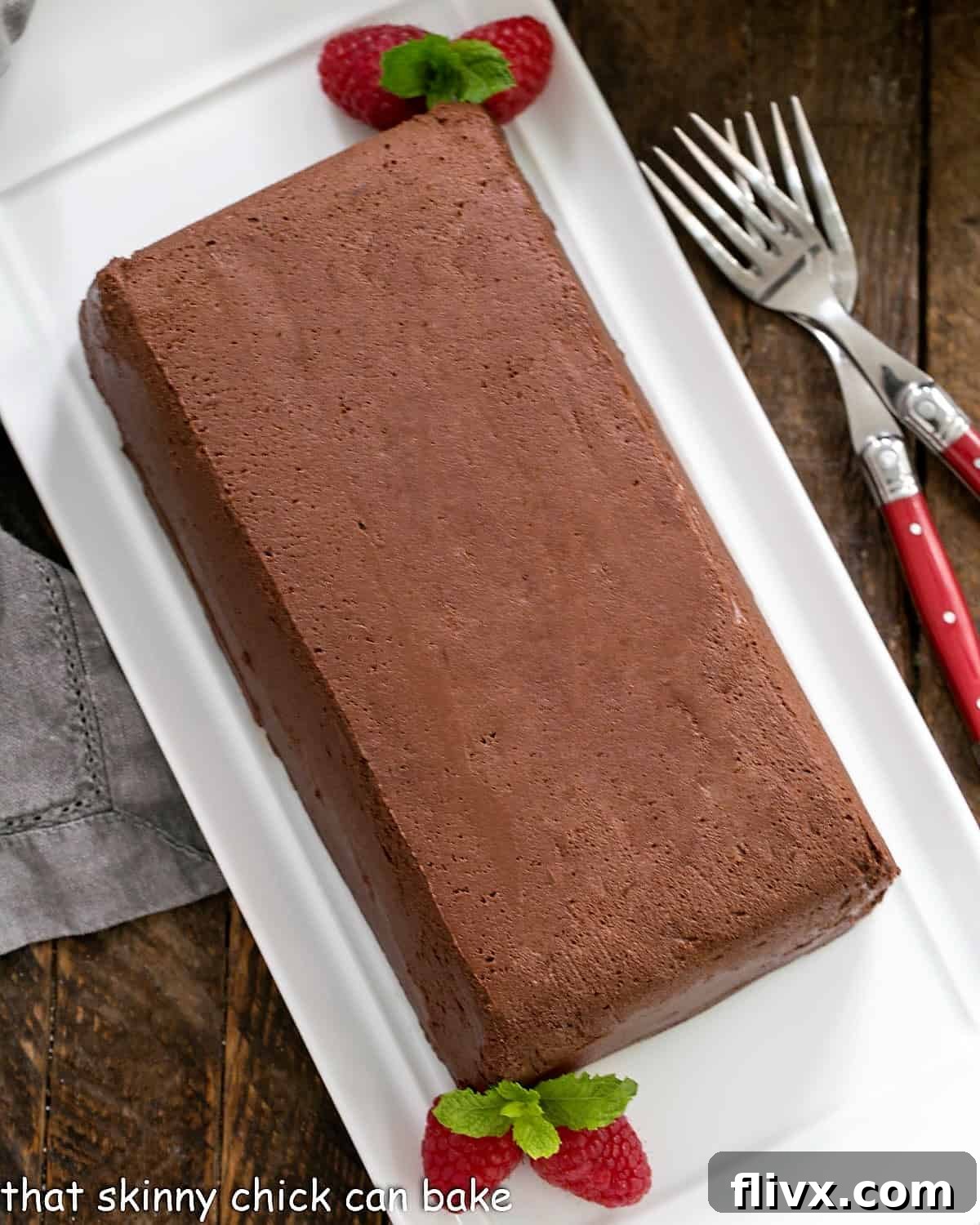 Chocolate Terrine with Raspberries and mint garnish on a white serving tray.