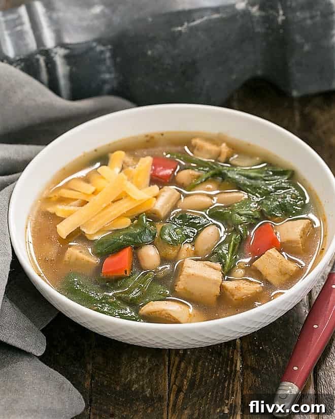 White Chicken Chili in a white basketweave bowl, garnished with fresh cilantro and a dollop of sour cream.