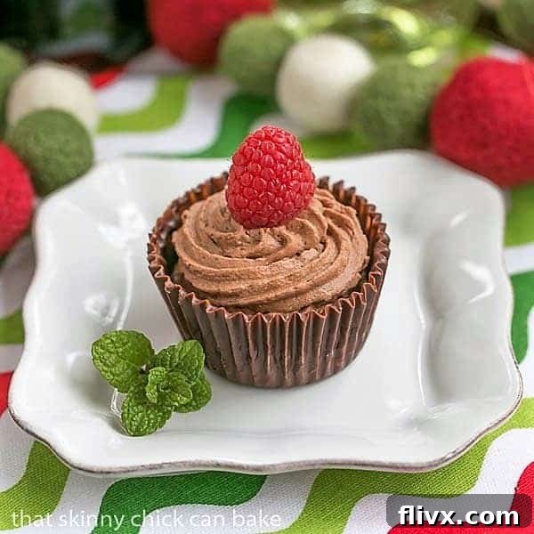 Homemade Chocolate Mousse Cups on a small white plate, garnished with a vibrant raspberry and a fresh mint leaf, showcasing their elegant presentation and rich dark chocolate