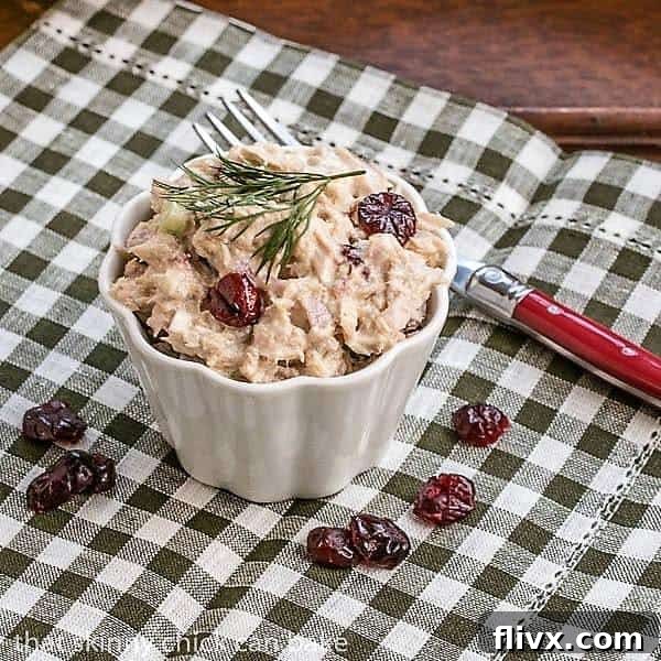 A close-up shot of the Tuna, Cranberry, Pecan Salad served in a small elegant white ramekin, showcasing its vibrant colors and inviting textures.