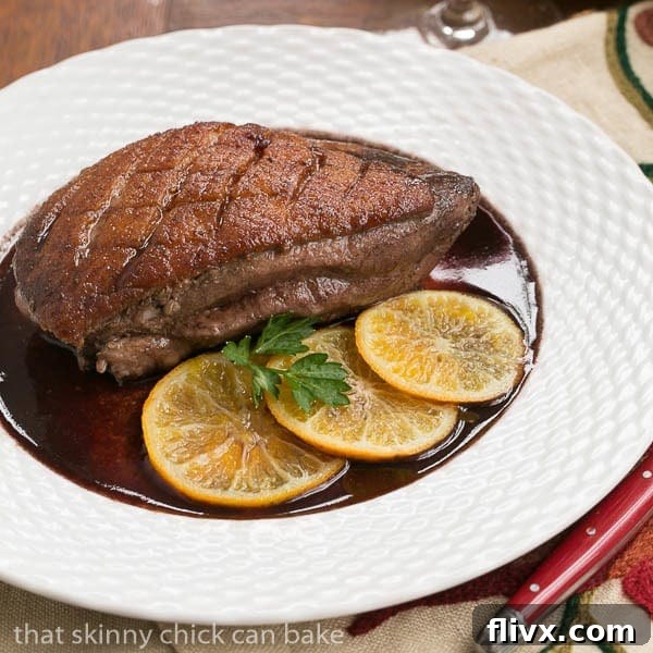 Pan Seared Duck Breasts on a white basketweave plate, garnished with clementines and herbs.