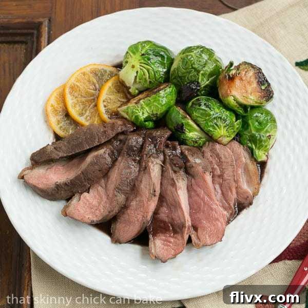 Pan Seared Duck Breasts on a plate with orange slices and Brussels sprouts.