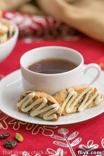 Cherry Pistachio Biscotti arranged artfully on a saucer next to a steaming cup of tea, inviting a moment of calm indulgence.