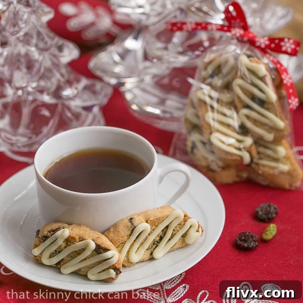 Cherry Pistachio Biscotti beautifully arranged on a white saucer with a cup of tea, with festively wrapped gift bags of biscotti in the soft-focus background, highlighting their gift potential.
