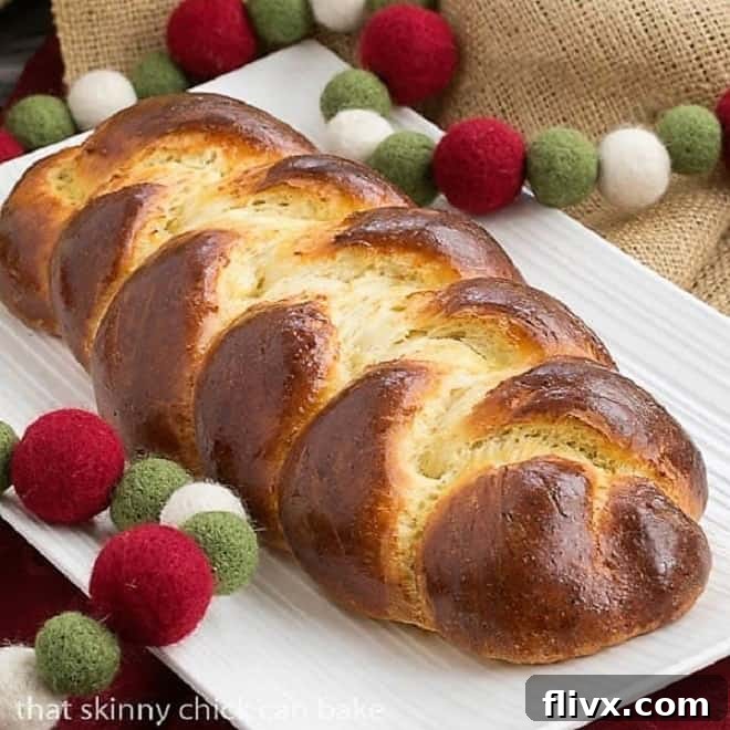 Beautiful golden-brown loaf of Swiss Butter Braid (Butterzopf) on a white platter, ready to be served, highlighting its intricate braid and glossy crust.