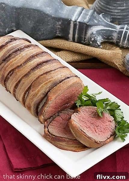 A stunning beef tenderloin with Gorgonzola Sauce, elegantly wrapped in bacon, presented on a pristine white platter for a festive meal.