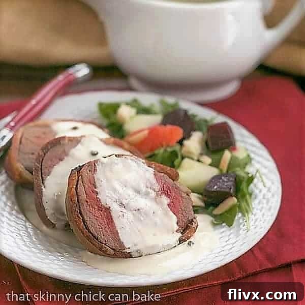 Delightful slices of perfectly cooked Beef Tenderloin, generously topped with creamy Gorgonzola Sauce, arranged on a white serving plate.