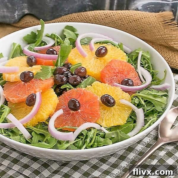 Orange Olive Salad served on a bed of fresh arugula in a pristine white bowl, showcasing its vibrant colors and inviting texture.