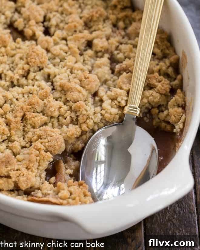 Easy Apple Crisp in a white ceramic baking dish with a serving spoon, inviting a comforting dessert experience.