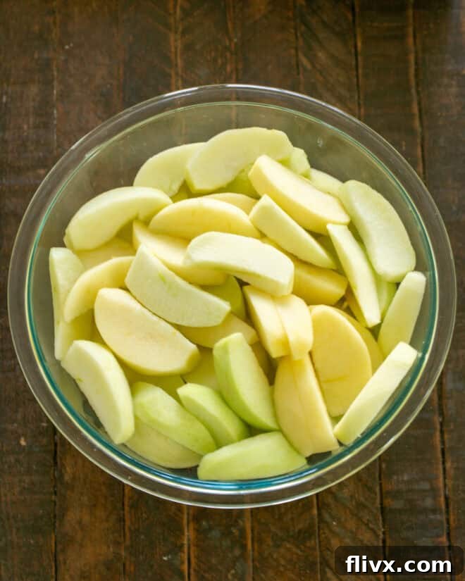 Apples freshly peeled, cored, and sliced for apple crisp.