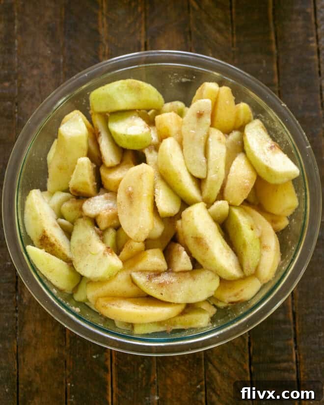 Apple crisp filling mixed, ensuring apples are evenly coated with sugar and spices.