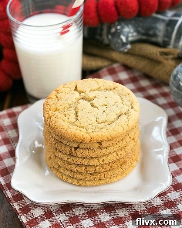 Close-up of golden Chewy Butterscotch Cookies on a white plate, served with a glass of cold milk, highlighting their soft texture and crackled tops.