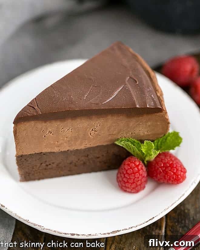 Frozen Chocolate Mousse Cake on a white dessert plate with fresh raspberries and mint.