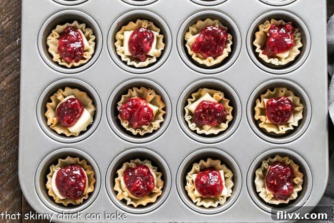 Unbaked Brie appetizers arranged in a mini muffin tin, ready for baking