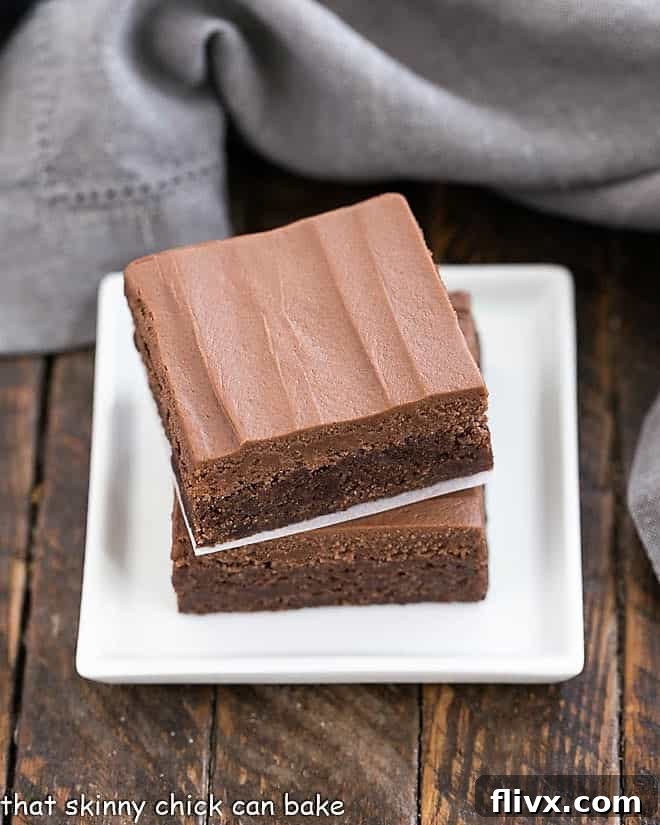 Frosted Brownies Recipe stacked on a small white plate, showing the rich chocolate frosting.