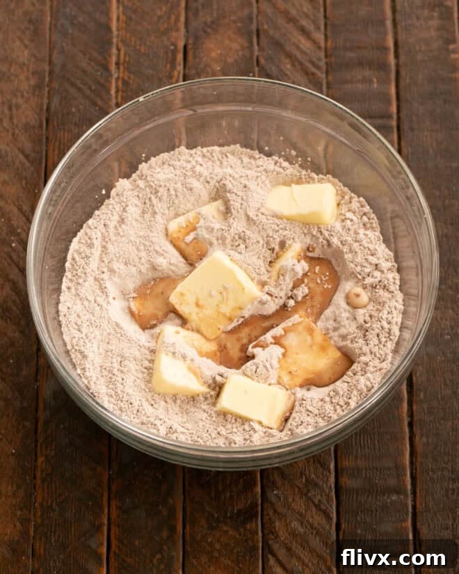 Ingredients for chocolate buttercream frosting being beaten together in a mixing bowl.