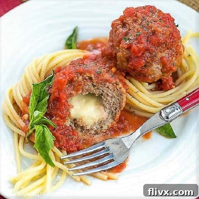 Mozzarella Stuffed Meatballs intertwined with spaghetti and garnished with basil.