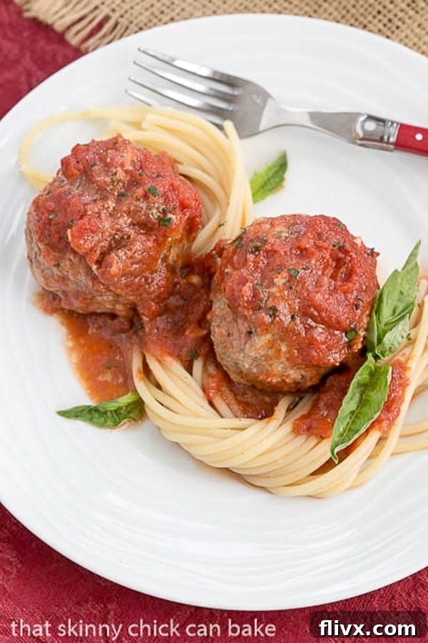 Mozzarella Stuffed Meatballs with pasta on a white plate.