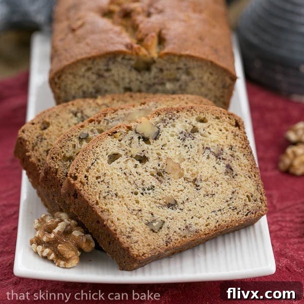 A loaf of banana nut bread and slices on a white tray. A perfectly baked loaf of banana nut bread, showcasing the golden crust and tender slices, achieved with careful pan preparation.