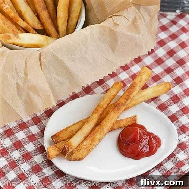 THIN AND CRISPY FRIES 2 Thin Crispy French Fries on a white plate with a dollop of ketchup, glistening and perfectly golden.