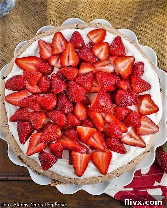 Overhead shot of Strawberry Topped Chocolate Pavlova on a ruffled white cake plate, highlighting the fresh berries and cream