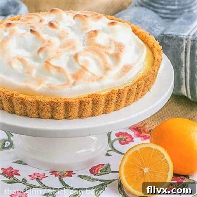 A stunning Meyer Lemon Tart with Meringue Topping, set on a elegant white cake stand, surrounded by fresh Meyer lemons