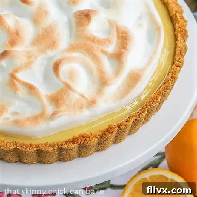 A close-up view of a slice of Meyer Lemon Tart with Meringue Topping on a cake stand, revealing its layers
