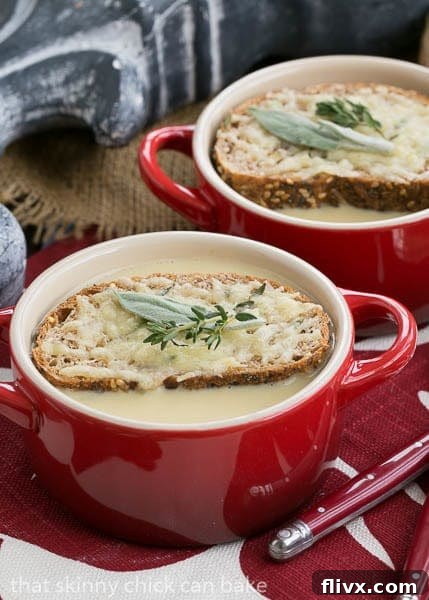 A bowl of Hangover Soup generously topped with golden cheesy toasts and fresh herbs, steam rising, promising warmth and relief.