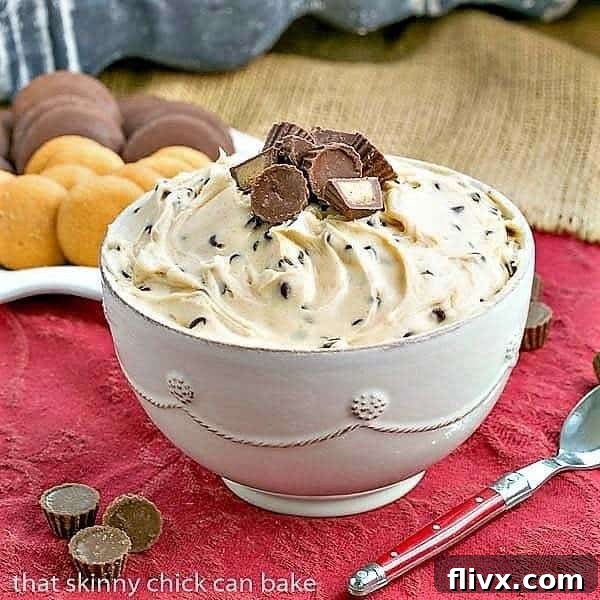 A smooth, creamy Peanut Butter Tagalong Dip in a ceramic serving bowl, garnished with miniature Reese's peanut butter cups, accompanied by a red-handled spoon, ready to be enjoyed.