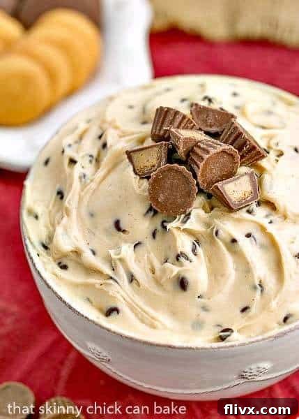 A close-up shot of the creamy Tagalong Dip presented in a pristine white serving bowl, garnished with miniature Reese's peanut butter cups and a sprinkle of chocolate chips, highlighting its delicious texture.