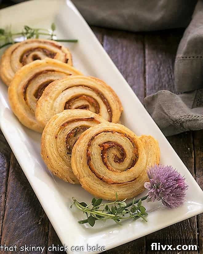 Honey Mustard Pepperoni Pinwheels on a white ceramic tray with a blossoming chive.